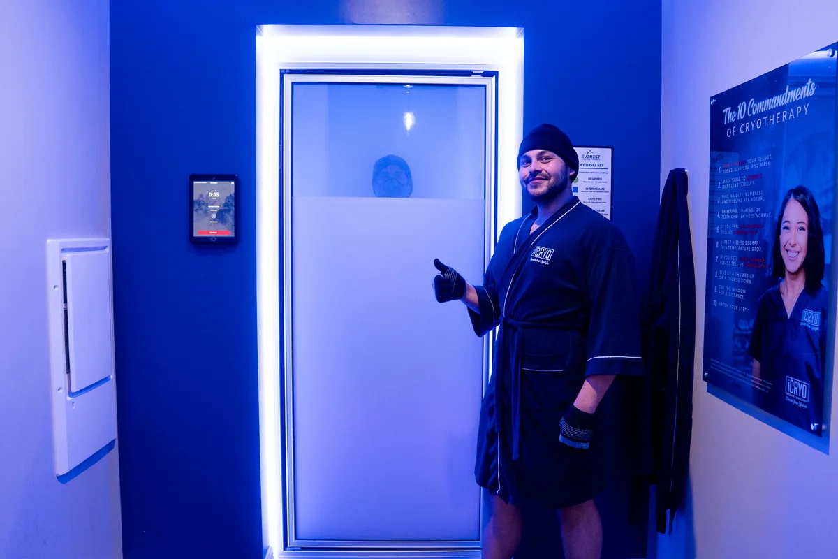 Client standing beside a cryotherapy chamber — iCRYO Westminster, CO wellness guide
