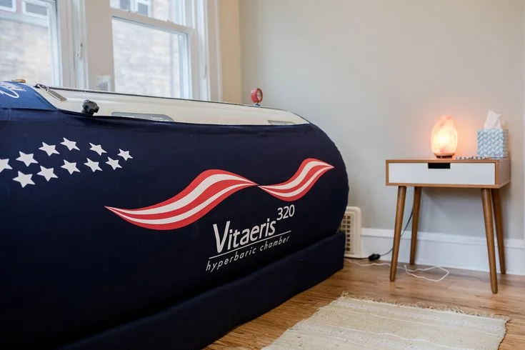 Vitaeris hyperbaric chamber beside a treatment-room table — iCRYO Westminster, CO wellness guide