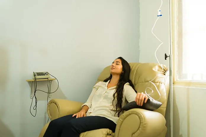 Client reclining in a chair beside an IV stand — iCRYO Westminster, CO wellness guide