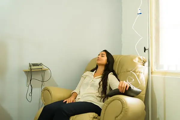 Client reclining in a chair beside an IV stand — iCRYO Westminster, CO wellness guide