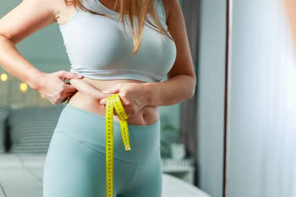 Woman measuring her waist during a weight-management routine — iCRYO Westminster, CO wellness guide
